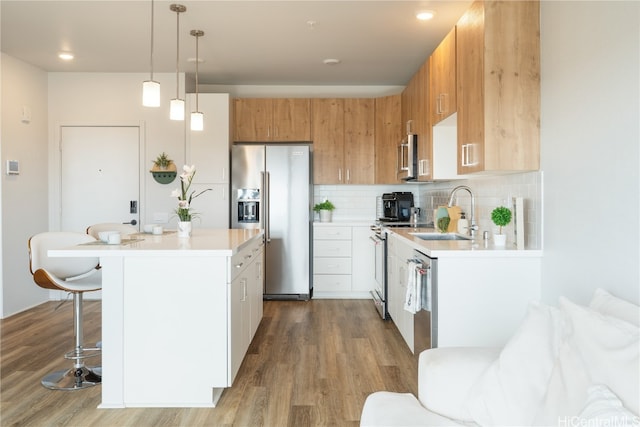 kitchen featuring sink, stainless steel appliances, backsplash, pendant lighting, and light hardwood / wood-style floors