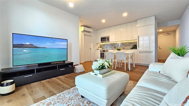 living room with a wall unit AC and light wood-type flooring