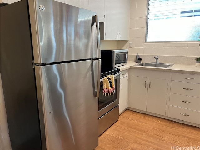 kitchen featuring white cabinets, appliances with stainless steel finishes, light hardwood / wood-style flooring, and sink