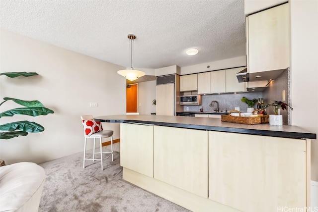 kitchen with stainless steel microwave, sink, backsplash, light colored carpet, and pendant lighting