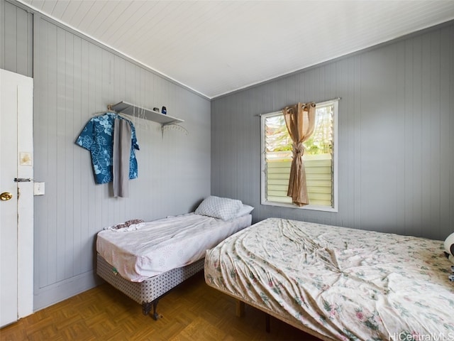 bedroom featuring parquet flooring and wooden walls