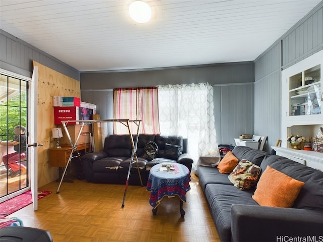 living room with crown molding, light parquet flooring, and wood walls