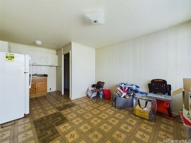 interior space with white fridge, white cabinetry, sink, and dark parquet flooring