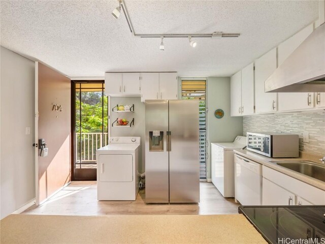 kitchen featuring stainless steel fridge, rail lighting, white dishwasher, white cabinets, and range hood