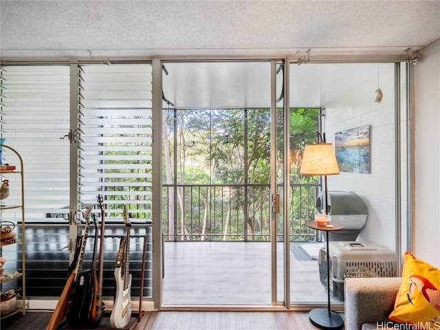 doorway featuring wood-type flooring, expansive windows, and a textured ceiling