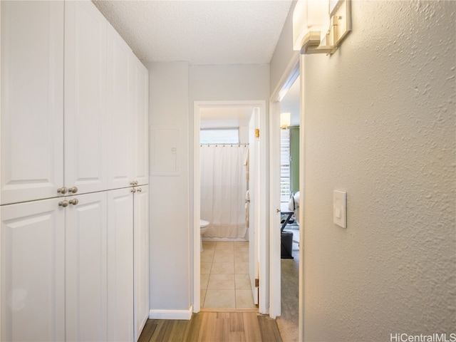 hallway featuring a textured ceiling, wood finished floors, and a textured wall