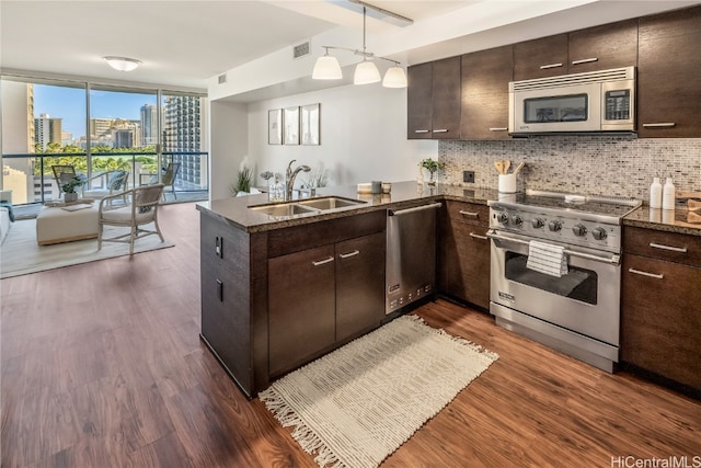 kitchen with kitchen peninsula, stainless steel appliances, sink, dark hardwood / wood-style flooring, and tasteful backsplash