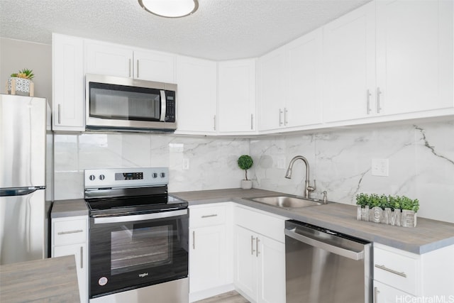 kitchen featuring wooden counters, appliances with stainless steel finishes, sink, and white cabinets