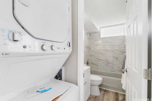 full bathroom with toilet, hardwood / wood-style floors, tiled shower / bath, vanity, and stacked washer and dryer