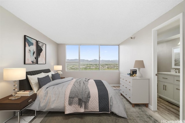 bedroom featuring a textured ceiling, a mountain view, and light hardwood / wood-style flooring