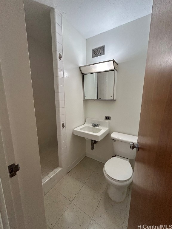 bathroom with toilet, walk in shower, sink, and tile patterned floors