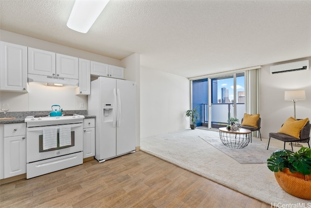 kitchen featuring a wall unit AC, white cabinets, light hardwood / wood-style flooring, range hood, and white appliances