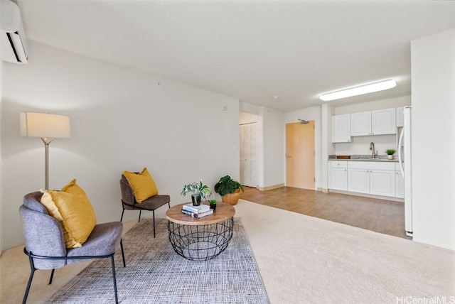 living area featuring sink, a wall unit AC, and light wood-type flooring