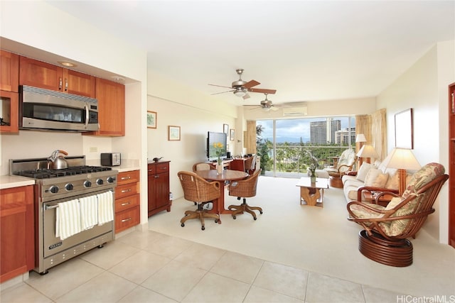 kitchen featuring a wall mounted air conditioner, light tile patterned flooring, stainless steel appliances, and ceiling fan