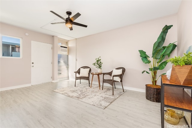 living area featuring a wall unit AC, light hardwood / wood-style flooring, and ceiling fan