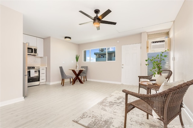 sitting room with light wood-type flooring, a wall mounted air conditioner, and ceiling fan