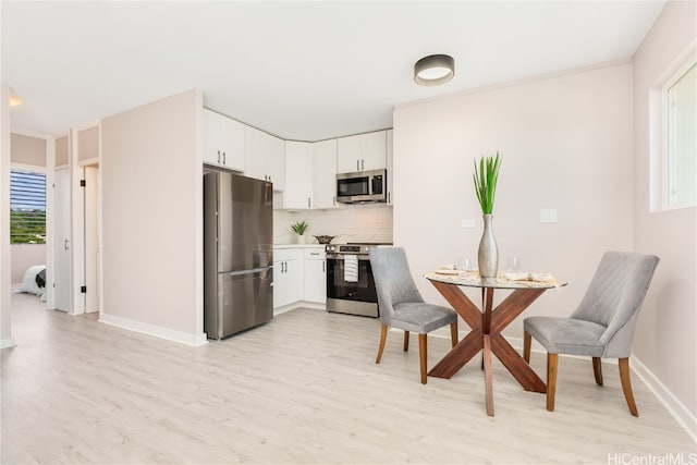 kitchen with appliances with stainless steel finishes, light hardwood / wood-style flooring, white cabinetry, and backsplash