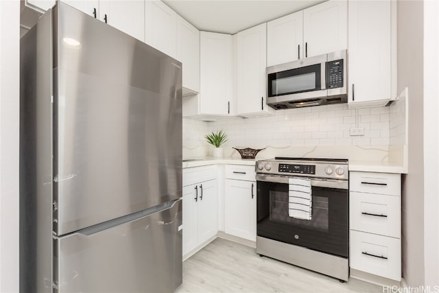 kitchen featuring stainless steel appliances, decorative backsplash, light wood-type flooring, and white cabinets