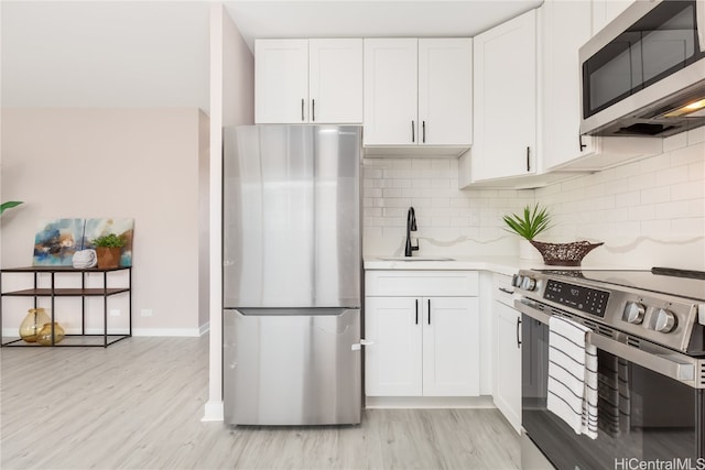 kitchen featuring light hardwood / wood-style flooring, stainless steel appliances, sink, and white cabinets