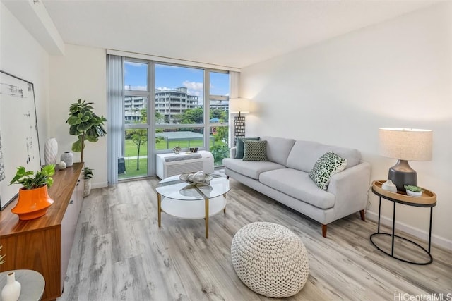 living room featuring floor to ceiling windows, a wall mounted AC, and light hardwood / wood-style flooring