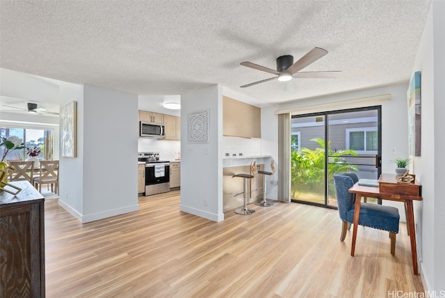 kitchen featuring a textured ceiling, light hardwood / wood-style floors, stainless steel appliances, ceiling fan, and light brown cabinets