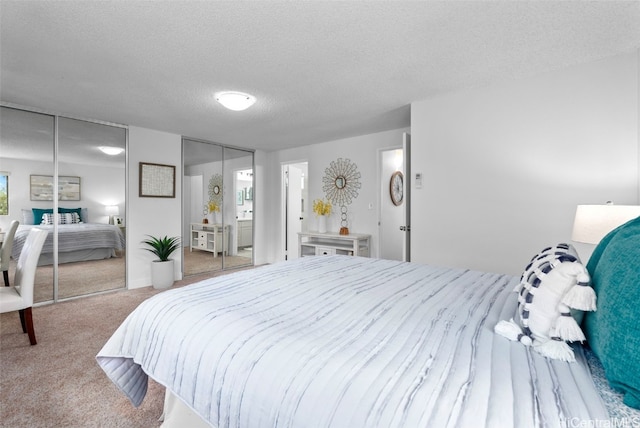 bedroom with a textured ceiling, two closets, and light colored carpet