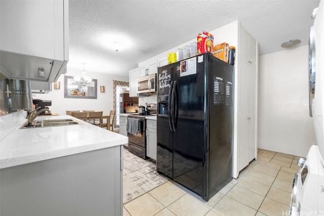 kitchen with black appliances, light tile patterned flooring, sink, a textured ceiling, and white cabinets