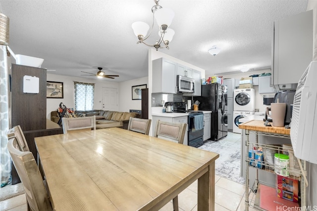 dining area featuring a textured ceiling, stacked washer / drying machine, ceiling fan with notable chandelier, and light tile patterned floors