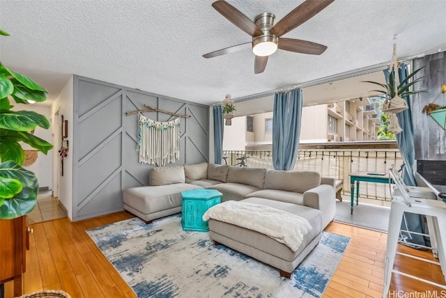 living room with light hardwood / wood-style flooring, a textured ceiling, and ceiling fan