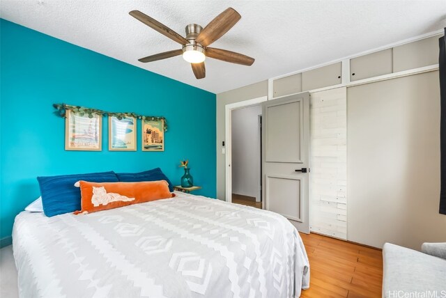 bedroom featuring light hardwood / wood-style floors, a textured ceiling, and ceiling fan