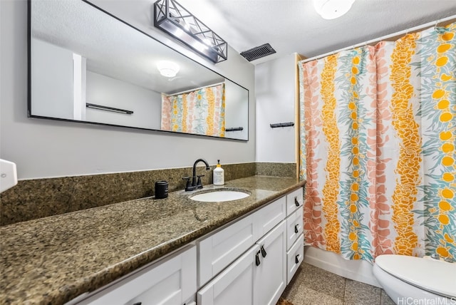 bathroom featuring vanity, a textured ceiling, and toilet