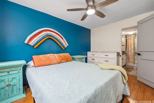 bedroom with a textured ceiling, ensuite bath, light wood-type flooring, and ceiling fan