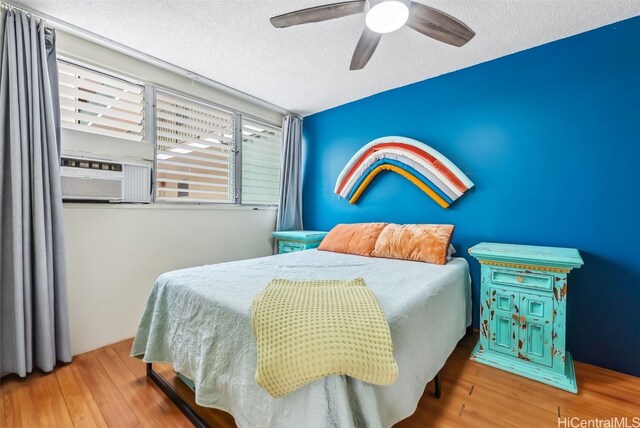 bedroom featuring cooling unit, a textured ceiling, hardwood / wood-style flooring, and ceiling fan