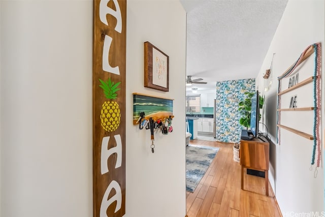 corridor with light hardwood / wood-style floors and a textured ceiling