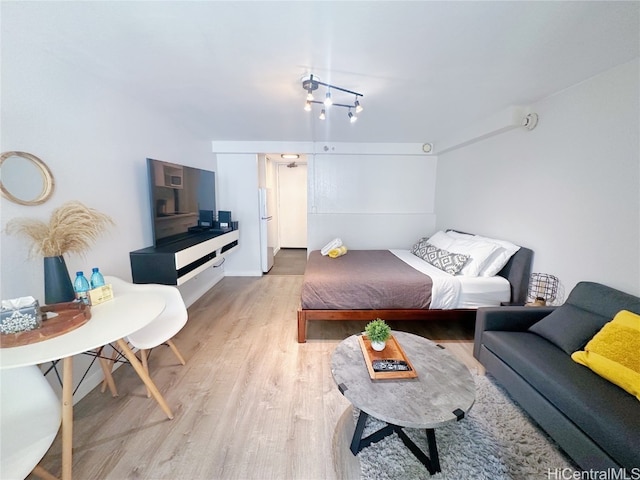 bedroom featuring light wood-type flooring and white refrigerator