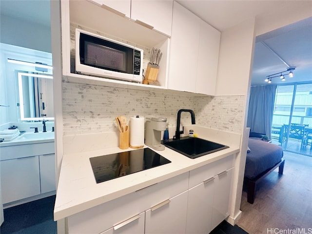 kitchen featuring sink, white cabinetry, decorative backsplash, and black electric cooktop