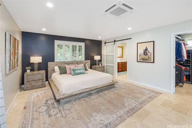 bedroom featuring a spacious closet, connected bathroom, a closet, and a barn door