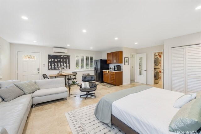 bedroom with stacked washer / dryer, a wall mounted air conditioner, light tile patterned floors, and black fridge