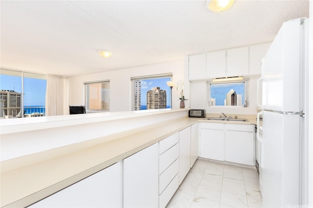 400 Hobron Ln Unit 3101, Honolulu, HI 96815 - kitchen featuring a sink, freestanding refrigerator, light marble finish flooring, light countertops, and white cabinetry
