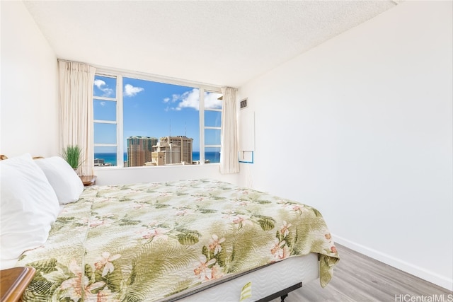 bedroom featuring a textured ceiling, wood-type flooring, and a water view