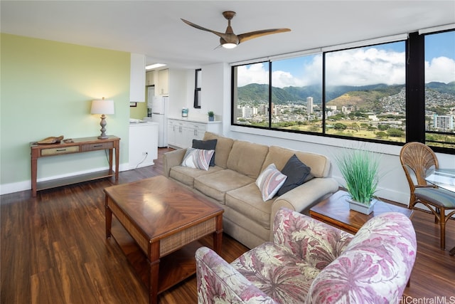 living room with a mountain view, dark wood-type flooring, and ceiling fan