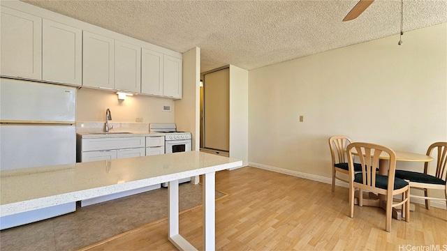 kitchen with white appliances, sink, a textured ceiling, white cabinetry, and light hardwood / wood-style flooring