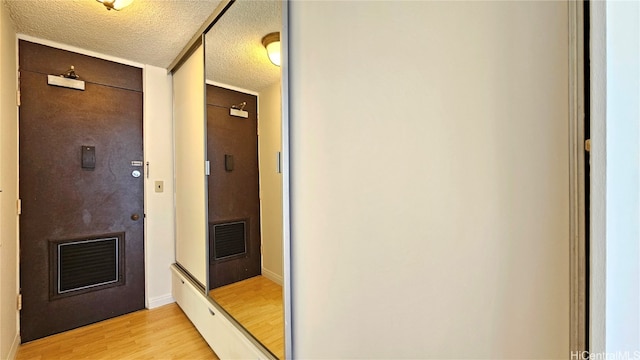 corridor featuring a textured ceiling and light wood-type flooring