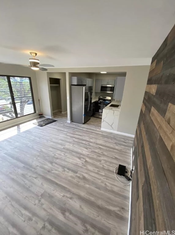 unfurnished living room featuring light wood-type flooring and ceiling fan