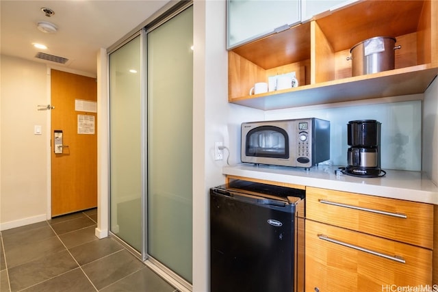 interior space with black refrigerator and dark tile patterned flooring