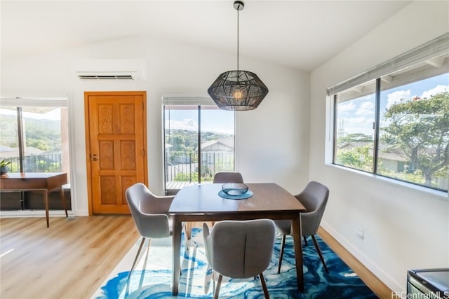 dining room featuring a wall unit AC, hardwood / wood-style floors, and lofted ceiling