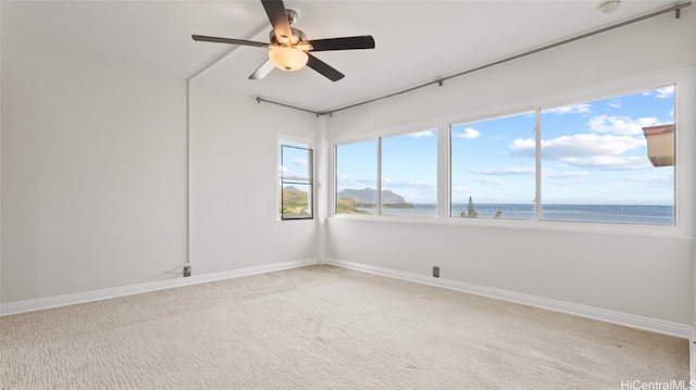 empty room featuring a water view, ceiling fan, and carpet