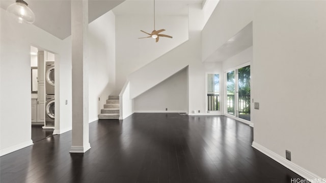 unfurnished living room with stacked washer / drying machine, a high ceiling, dark hardwood / wood-style floors, and ceiling fan