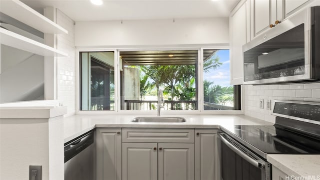 kitchen featuring white cabinets, light stone counters, backsplash, appliances with stainless steel finishes, and sink