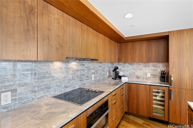 kitchen featuring tasteful backsplash, black appliances, light wood-type flooring, wine cooler, and extractor fan